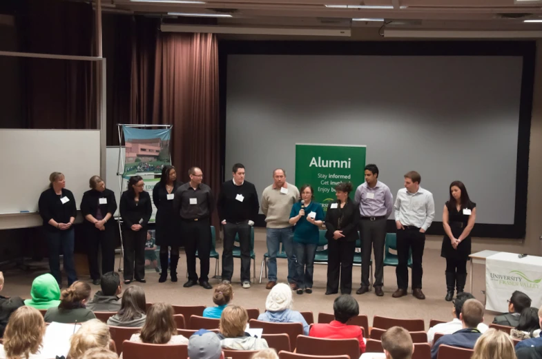 a group of people standing in front of a large audience