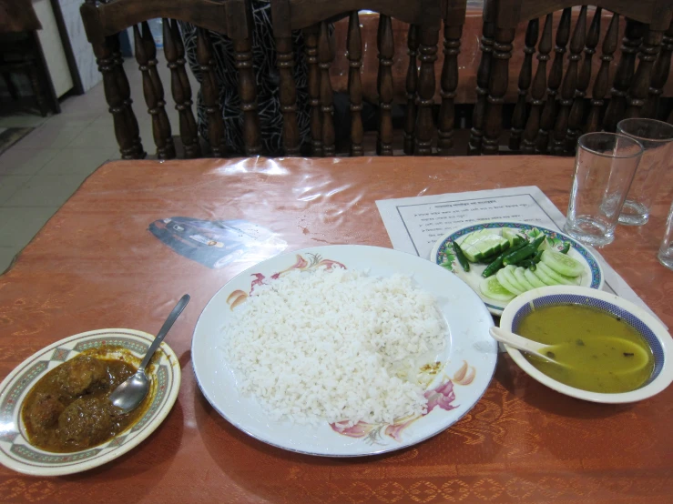 two plates of rice, a bowl of greens and some soup