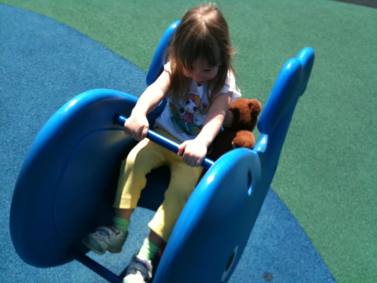 the little girl is sitting on the small swing