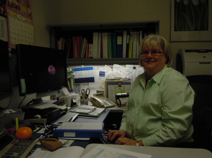 a woman sitting at her desk in front of computer monitor