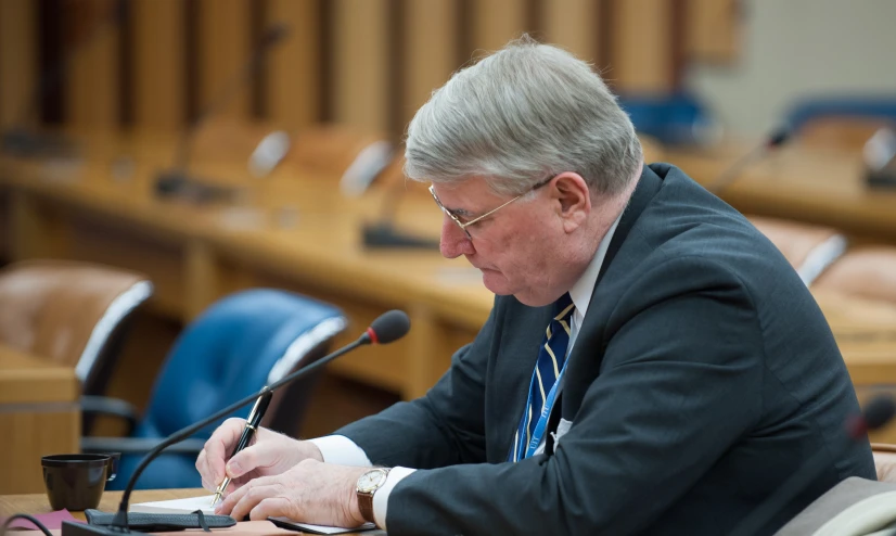 a man is sitting at a desk and making notes