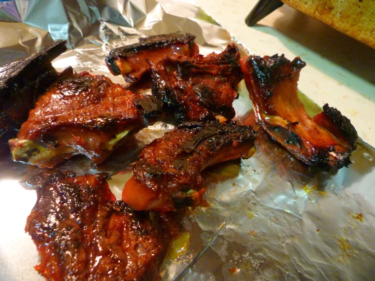 bbq ribs and carrots sitting on some foil on a table