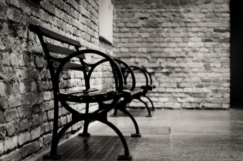 a brick wall and two empty benches in front of it