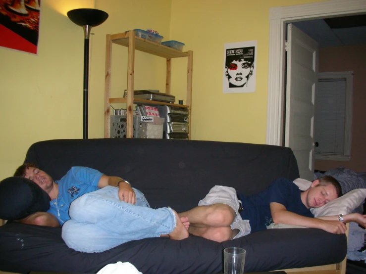 three people lying on a couch and one laying on the couch