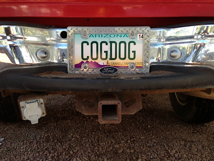 a license plate that is attached to the bumper of a red vehicle