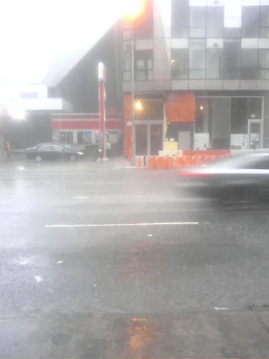 a street in the rain with traffic lights on the road