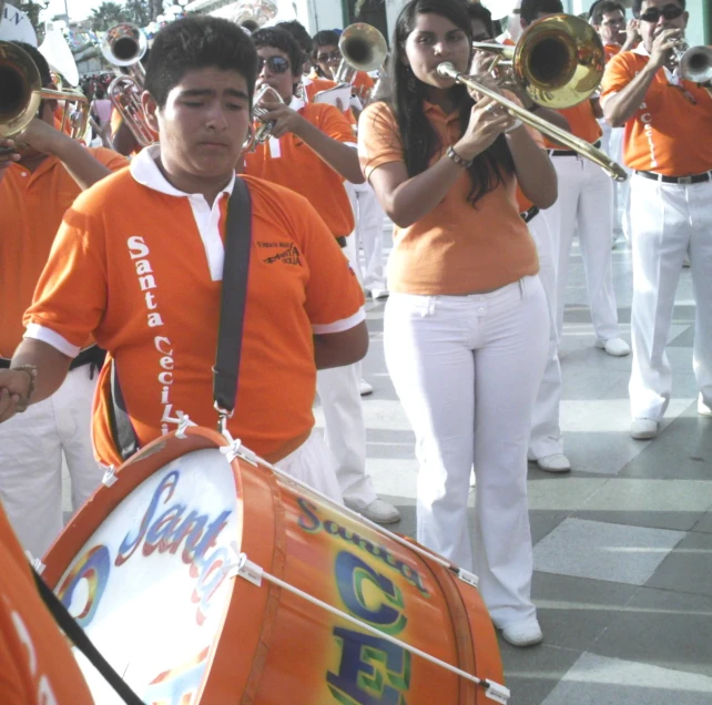 band members carrying instruments in orange and white outfits