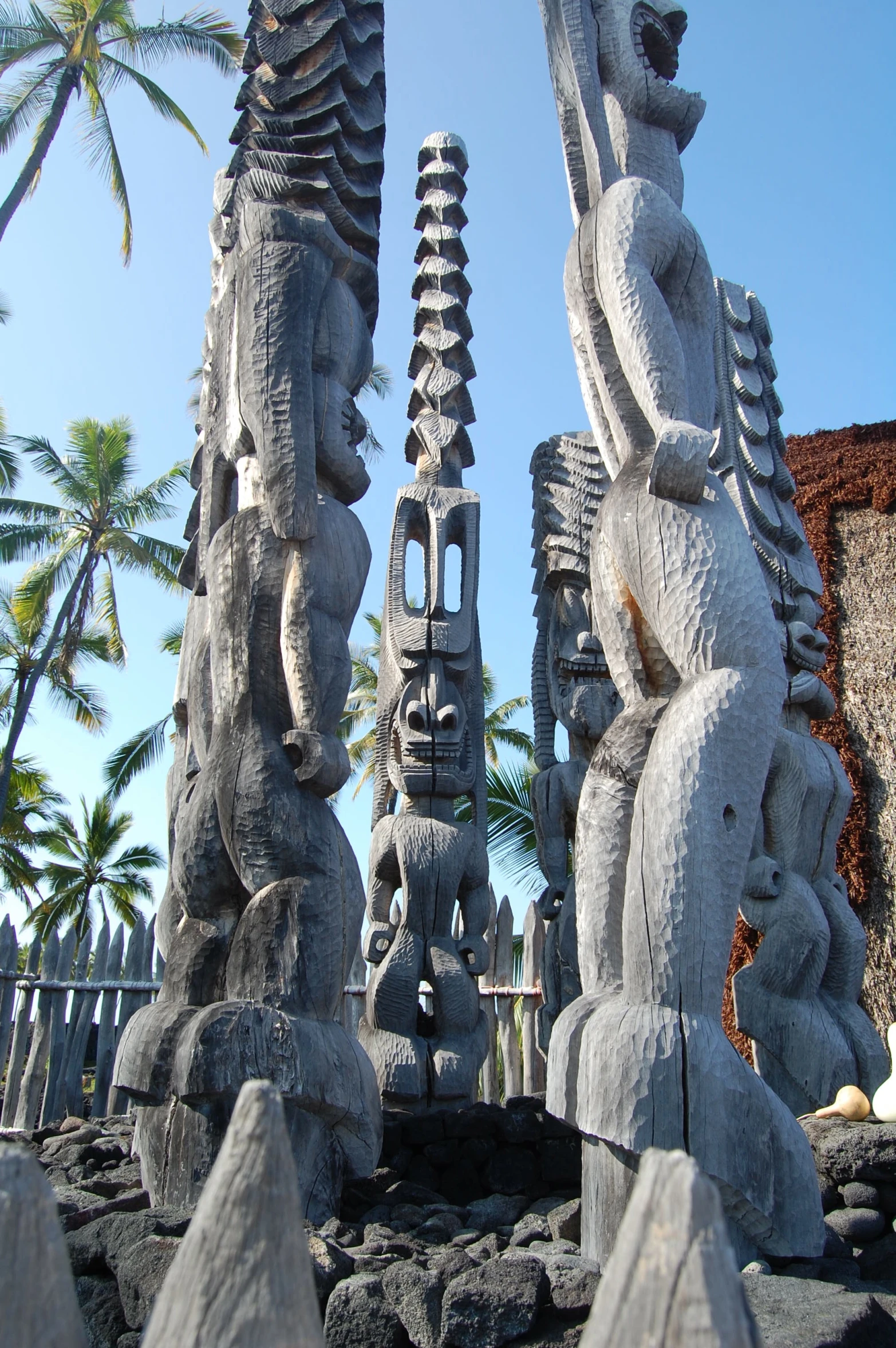 large carved gray stone sculptures in front of palm trees