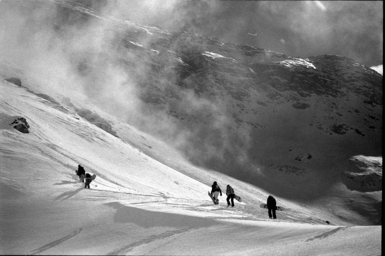 a black and white pograph of skiers coming down a snowy mountain