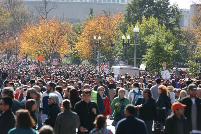 a crowd of people walking down a street next to tall buildings