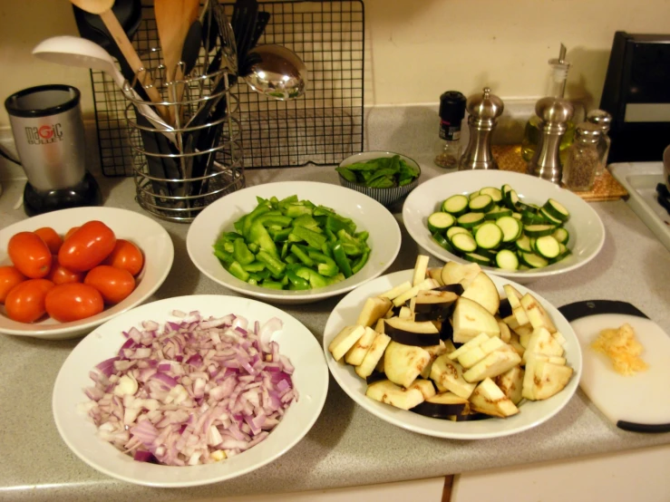 bowls of vegetables including tomato, cucumbers, red onions and green peppers