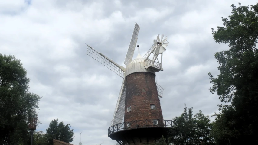 a large white windmill sitting next to a lush green forest