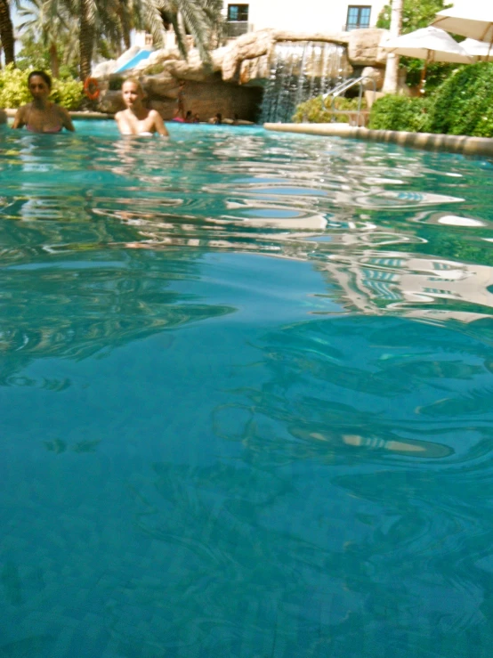 two people are swimming in a blue pool