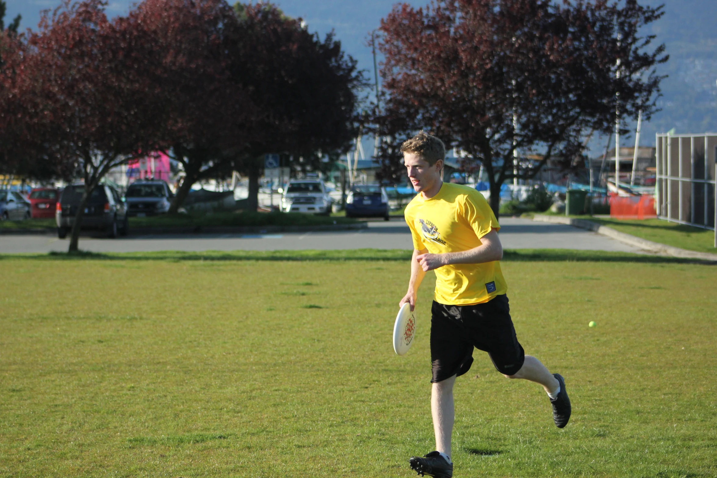 man in yellow shirt and black shorts playing catch in the park