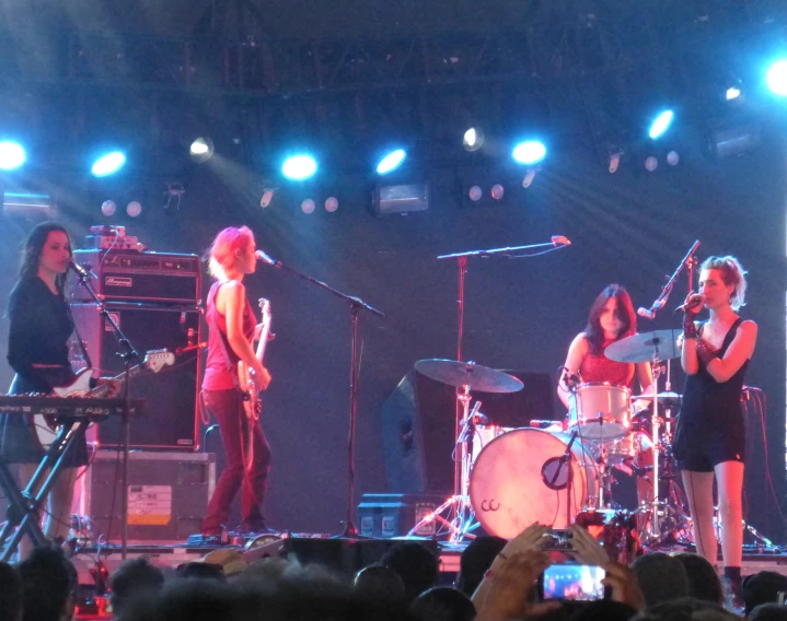 three female band members perform on stage with fans