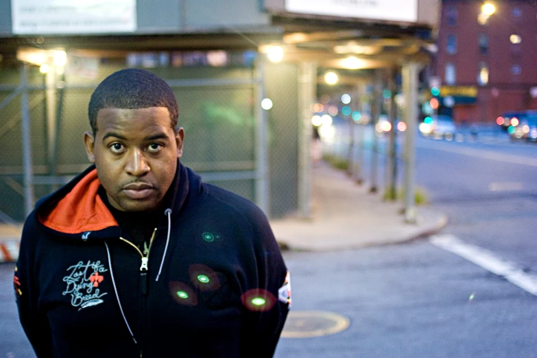 a man in an orange jacket standing on the sidewalk