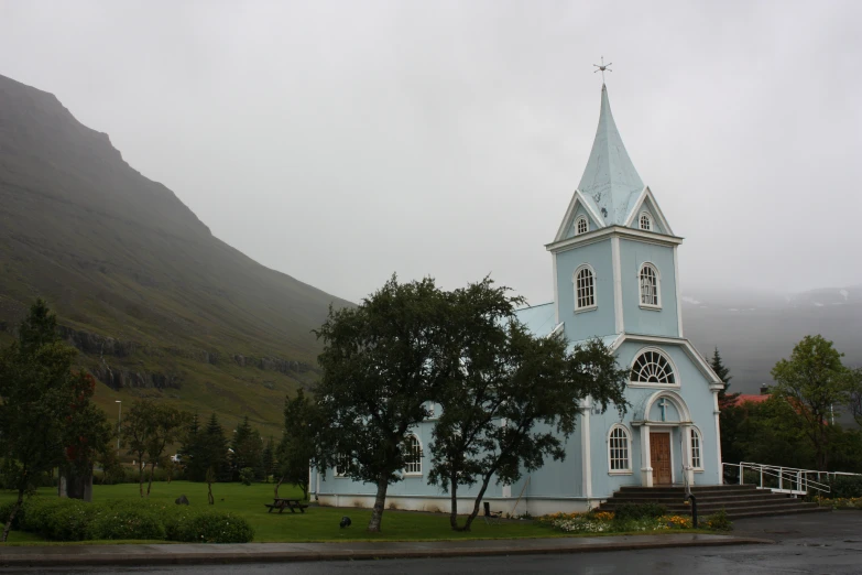 an old church on the side of a hill in the rain