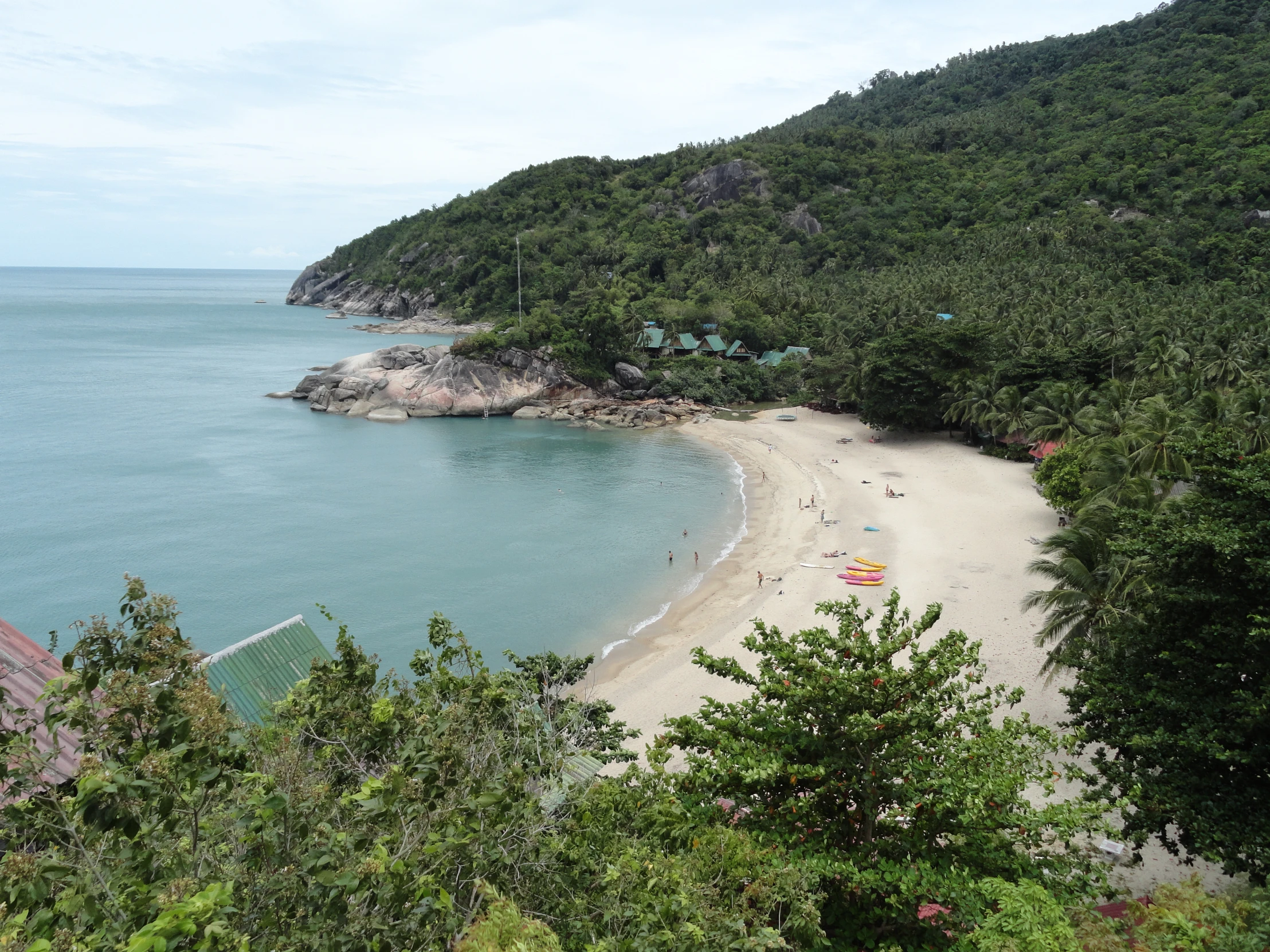 the view from above the cliff to a white sand beach and forest