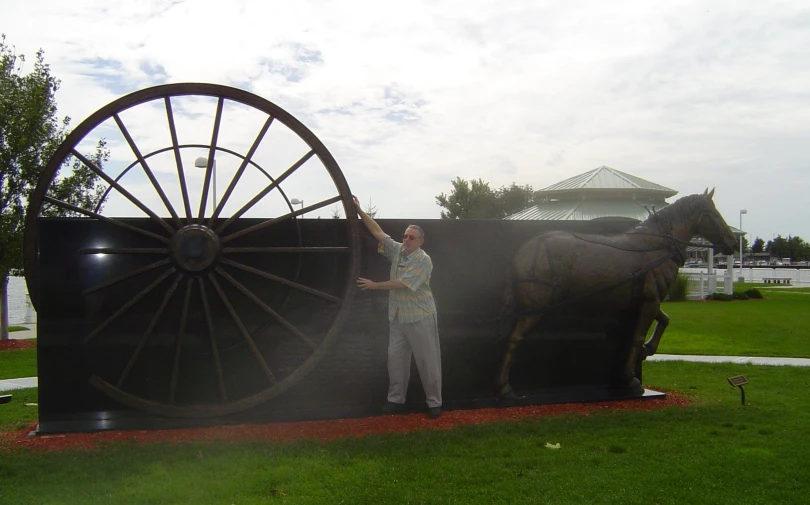 a man holding onto an outdoor sculpture of a horse and buggy