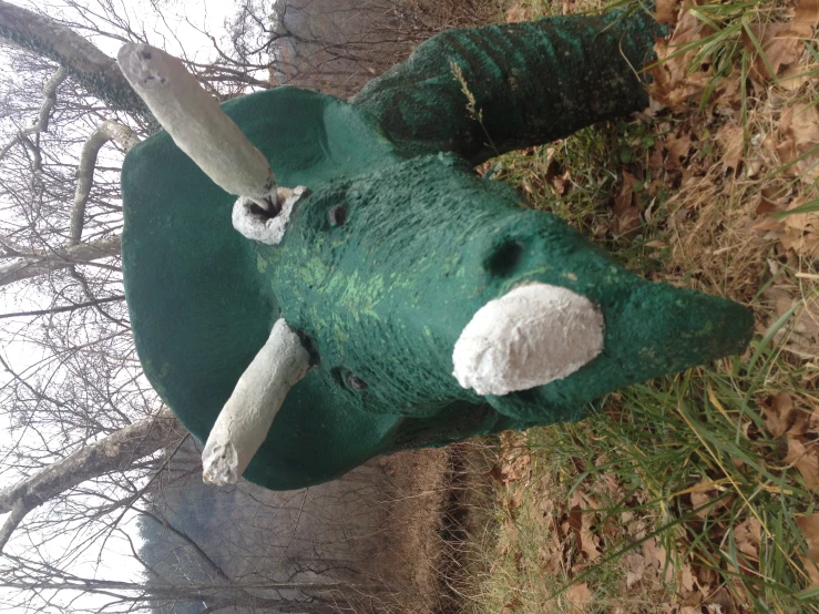 a green animal sculpture is made to look like it is lying on the ground