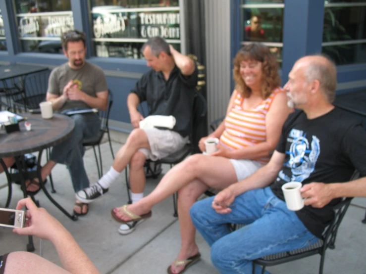 a group of people sit outside, holding drinks