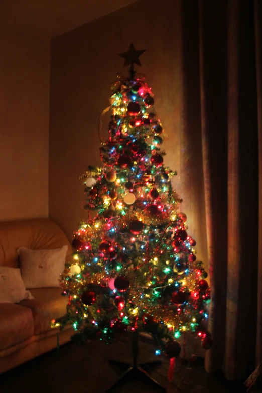 there is a brightly lit christmas tree in front of the window