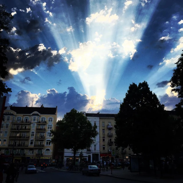 the sun's rays piercing through the clouds above a town square