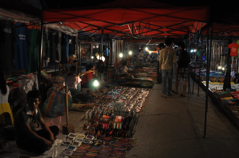 a night time scene of a market area with people shopping and lights on