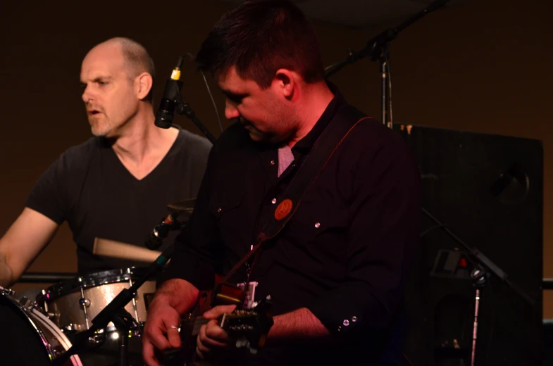 two men playing instruments on a stage at night