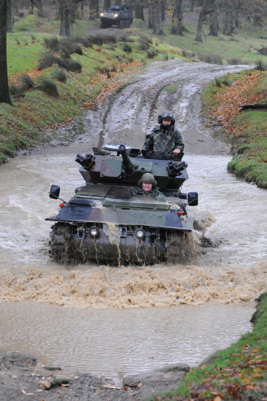 two military men ride a tank through a river