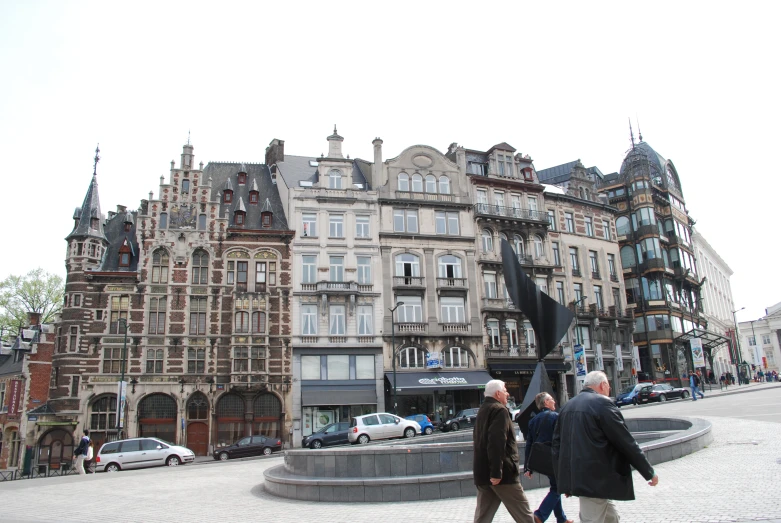 three people walk past some buildings that are older