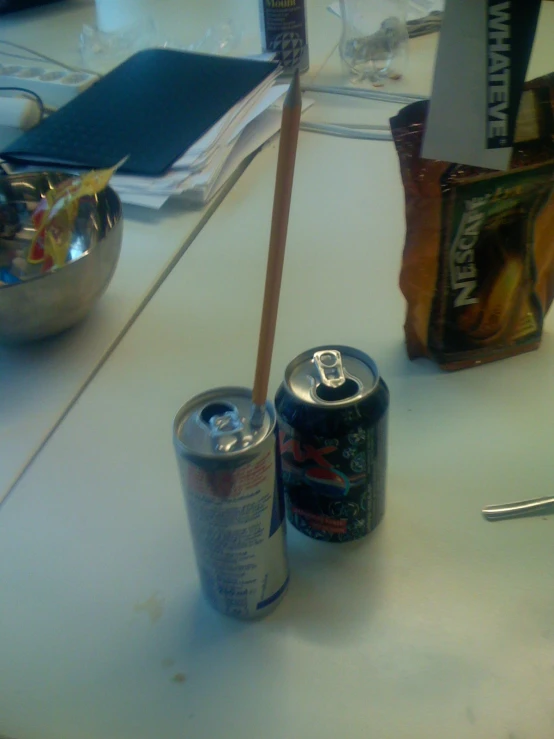 two cans of soda sitting on a counter in an office