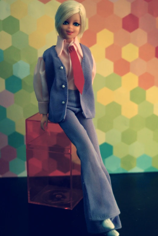 a doll posed on a suitcase, and dressed in business attire