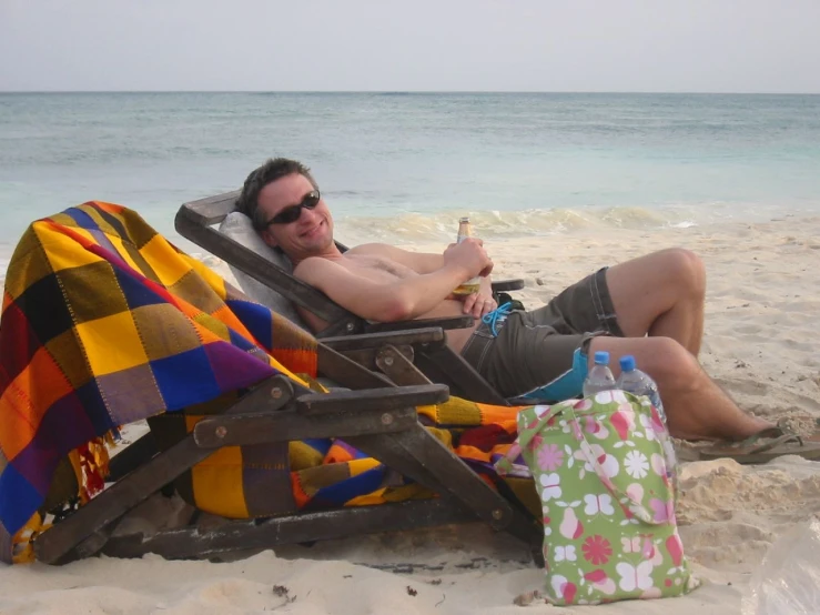 a man sits in an oversized beach chair on the beach