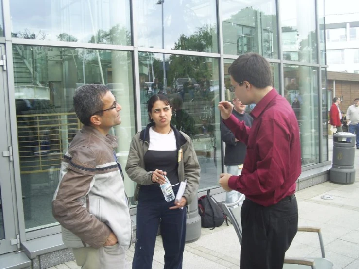 some people are standing near glass with luggage