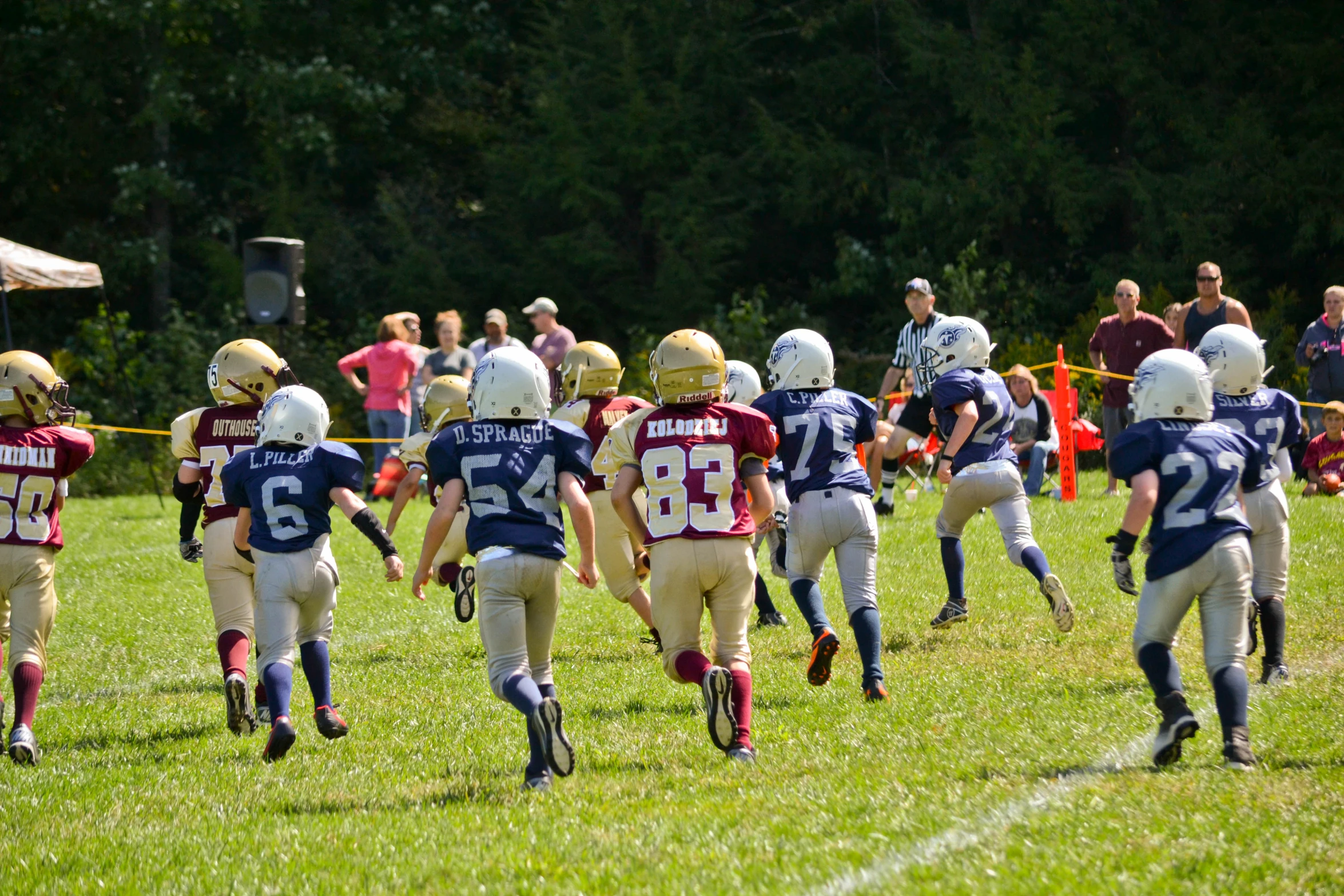 several young s in uniforms running on a field