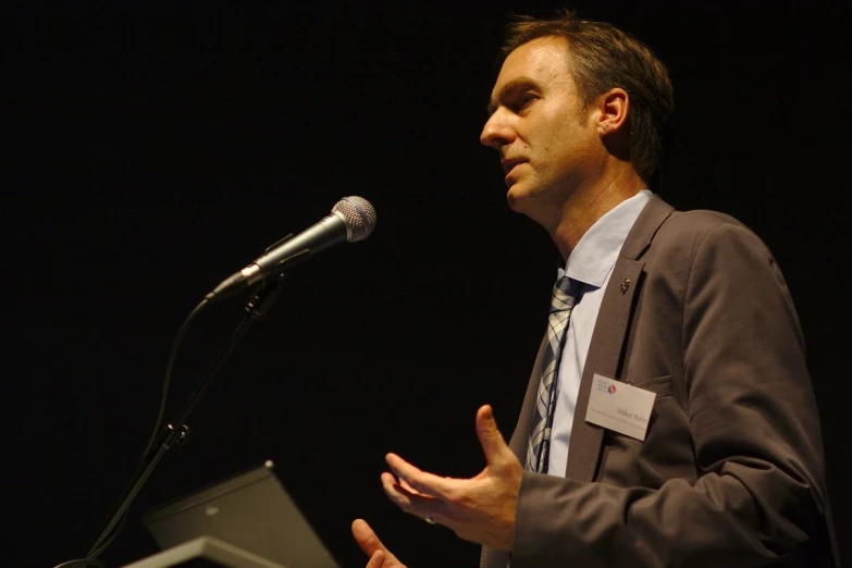 a man speaking at a podium while holding a laptop computer