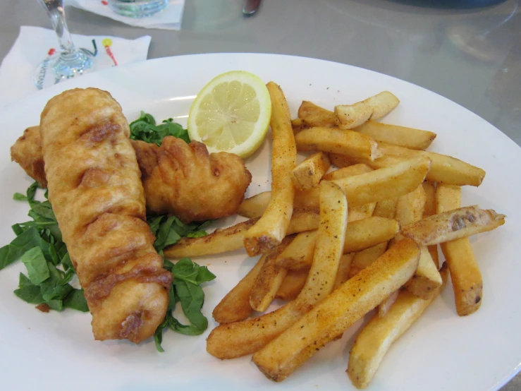 a plate with some french fries and some chicken and a lemon wedge
