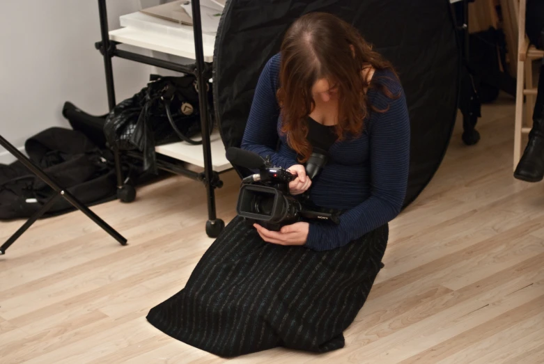 a woman sitting on the ground and looking at her camera