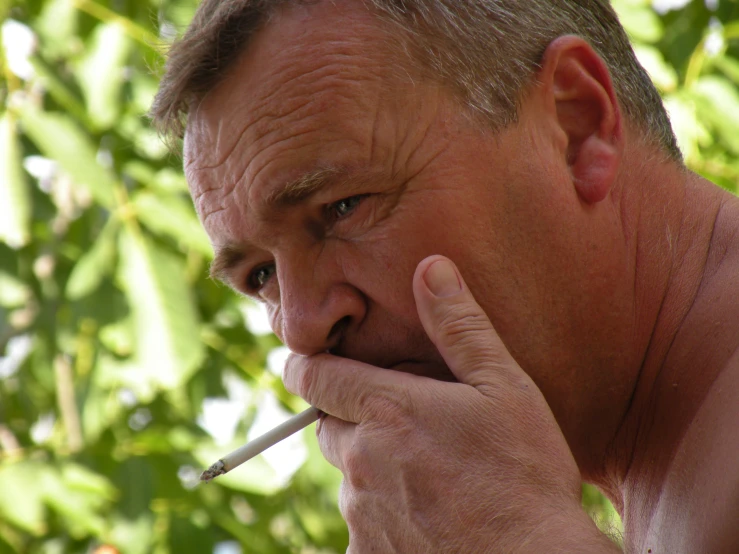 man in sunglasses smoking a cigarette with one hand