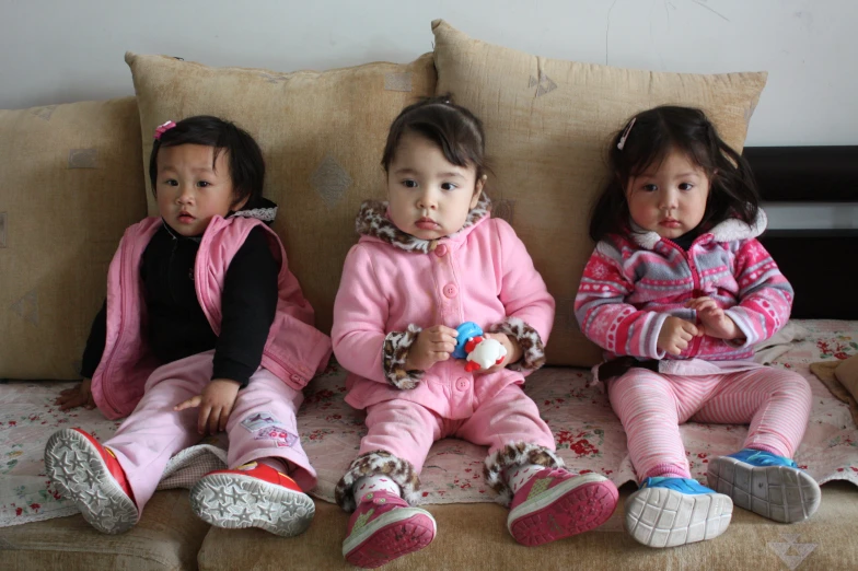 three little girls sitting together on top of a couch