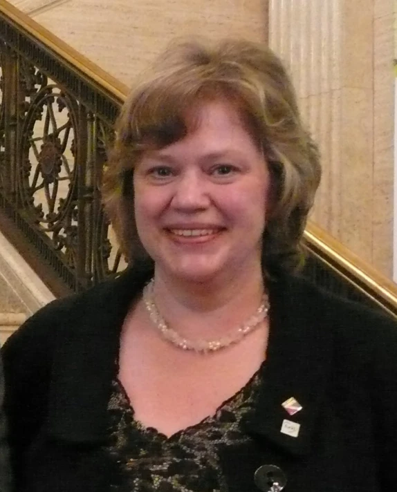 a smiling woman with a white necklace on her lap