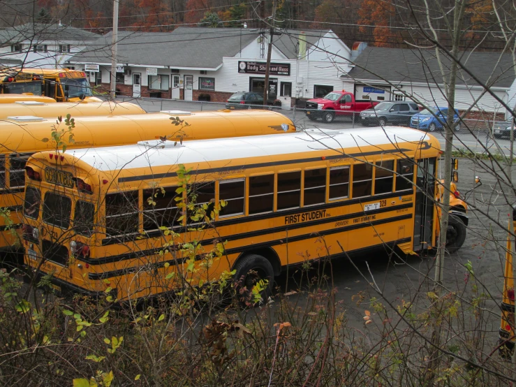 several yellow school buses parked in front of a small building