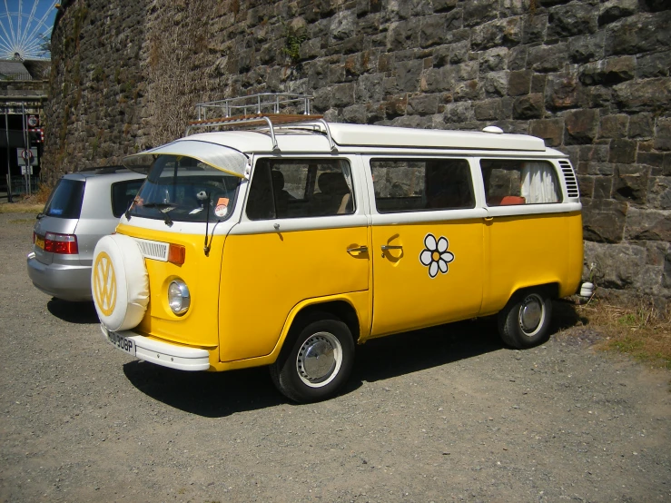 yellow and white vw type bus parked in front of a wall