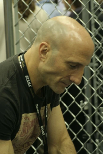 a man in black shirt leaning against a fence