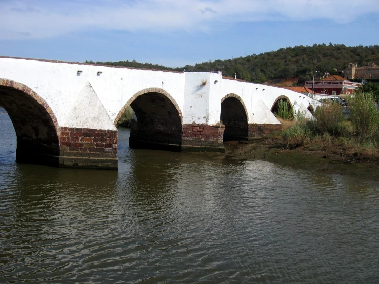 a stone bridge with a white wall and water running under it