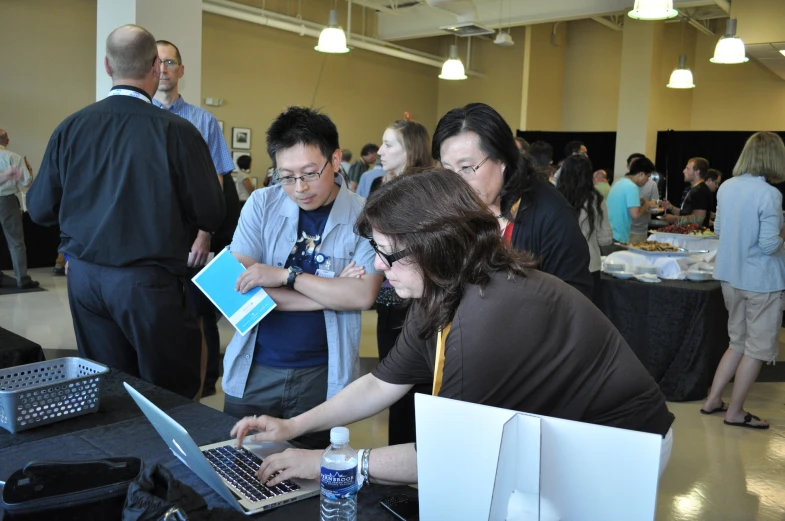 a man using his laptop computer next to some other people