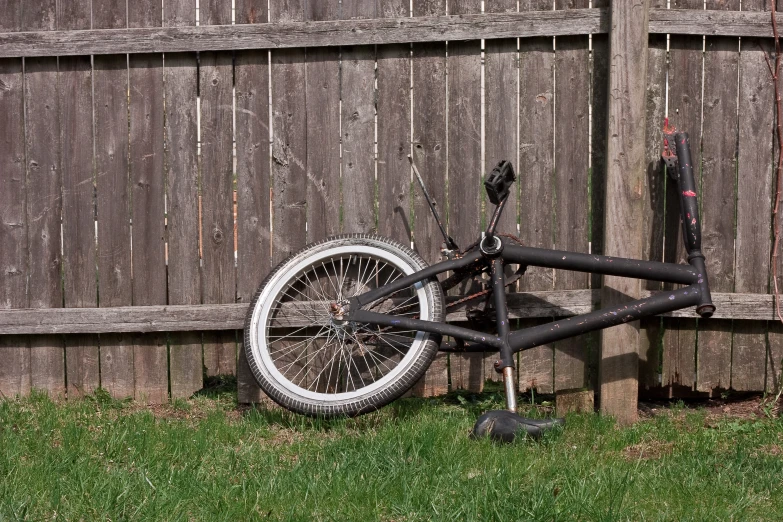 a bicycle leaning against a wooden fence