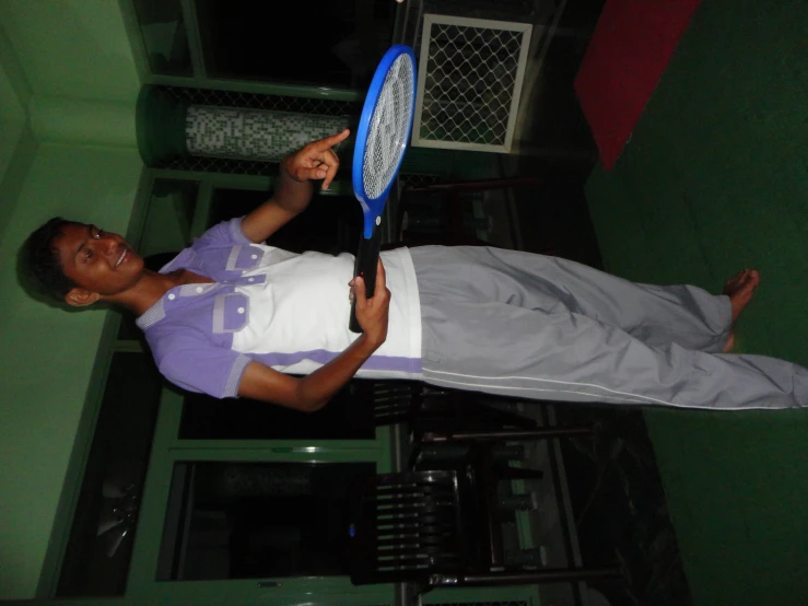 a young man standing on top of a green carpet holding a tennis racquet