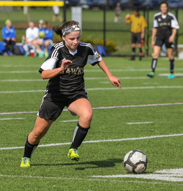 a soccer player running after a soccer ball on the field